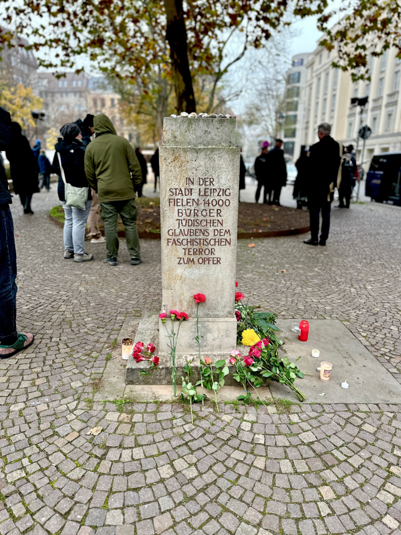Stein an der Gedenkstätte in der Gottschedstraße zur Erinnerung an die Opfer der Novemberpogrome mit Blumen.
