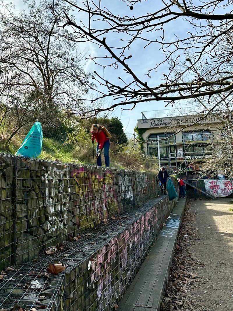 Claudia Maicher auf einer Mauer beim Müllsammeln am Karl-Heine-Kanal.